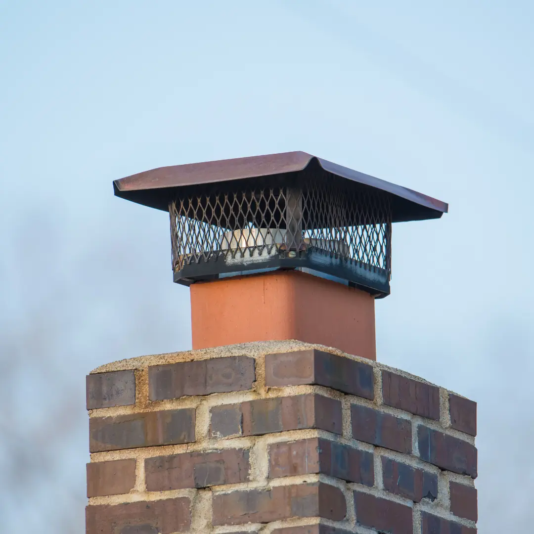 A close-up view of a brick chimney with visible soot buildup and signs of creosote accumulation inside the flue. The chimney interior appears dark and rough, with a partially obstructed passageway due to the buildup. The image highlights the need for cleaning and maintenance to prevent potential fire hazards.