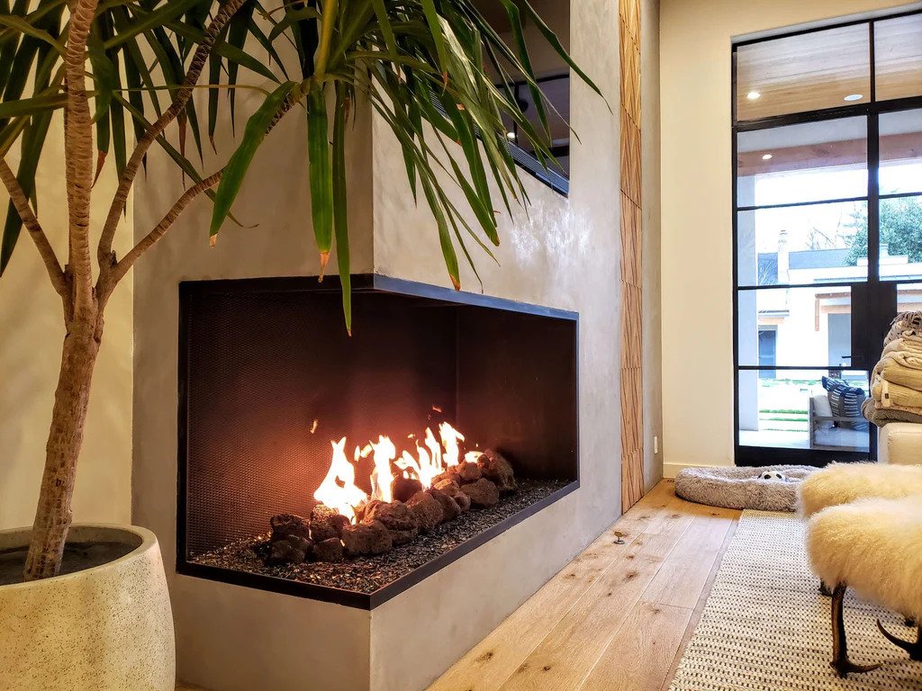 A modern fireplace in a stylish home, featuring a large window that allows natural light to illuminate the space.