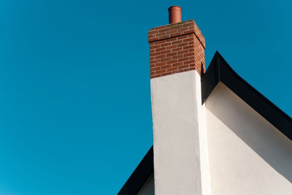 A chimney atop a house under a clear blue sky, showcasing a serene and picturesque residential scene.