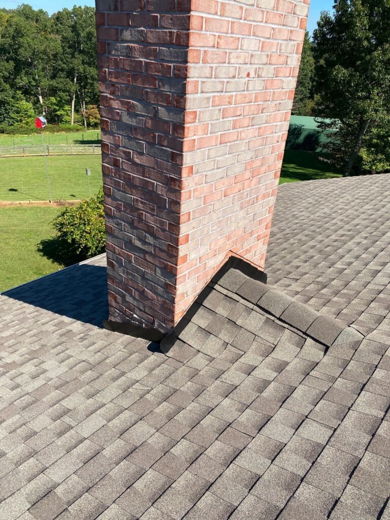 A brick chimney rising from a rooftop, showcasing traditional architecture against a clear sky.