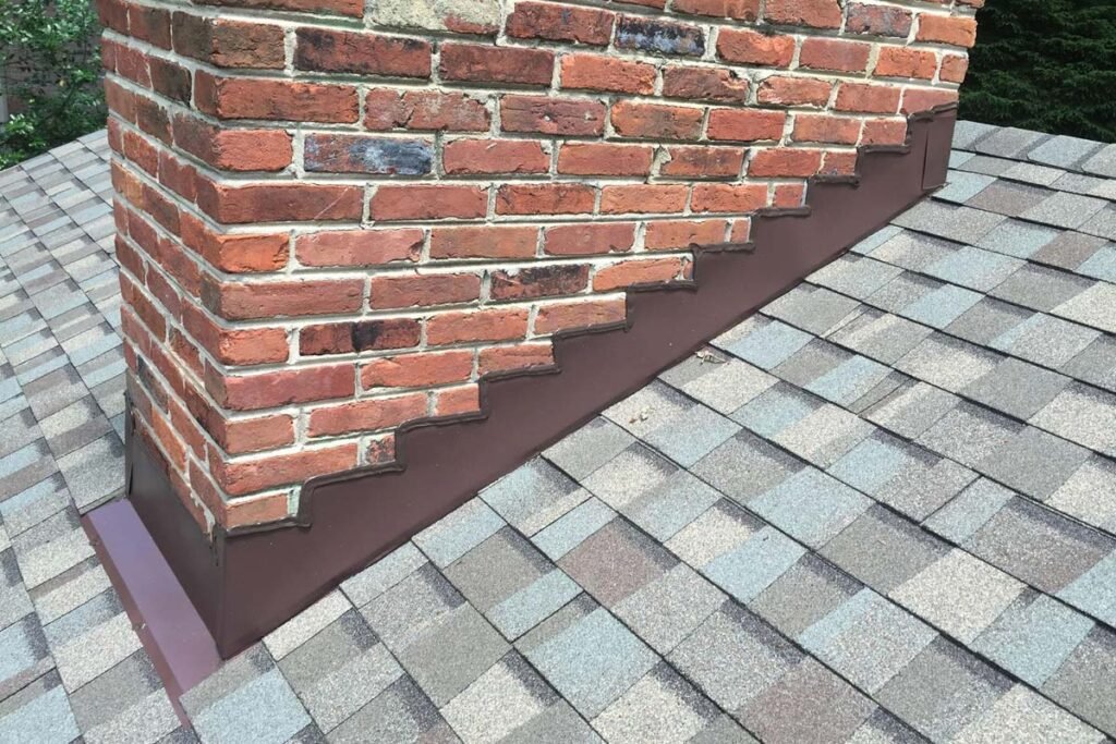 A brick chimney rises from a brown roof adorned with brown shingles, showcasing a classic architectural design.
